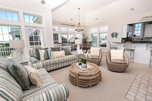 A spacious living room with a large sofa, a round coffee table, and a dining area with chairs.