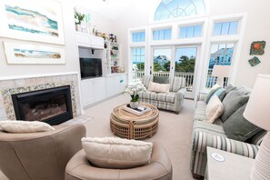 A spacious living room with a fireplace, comfortable seating, and a view of the outdoors.
