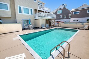 A swimming pool with a lifeguard stand, lounge chairs, and a covered seating area with umbrellas.