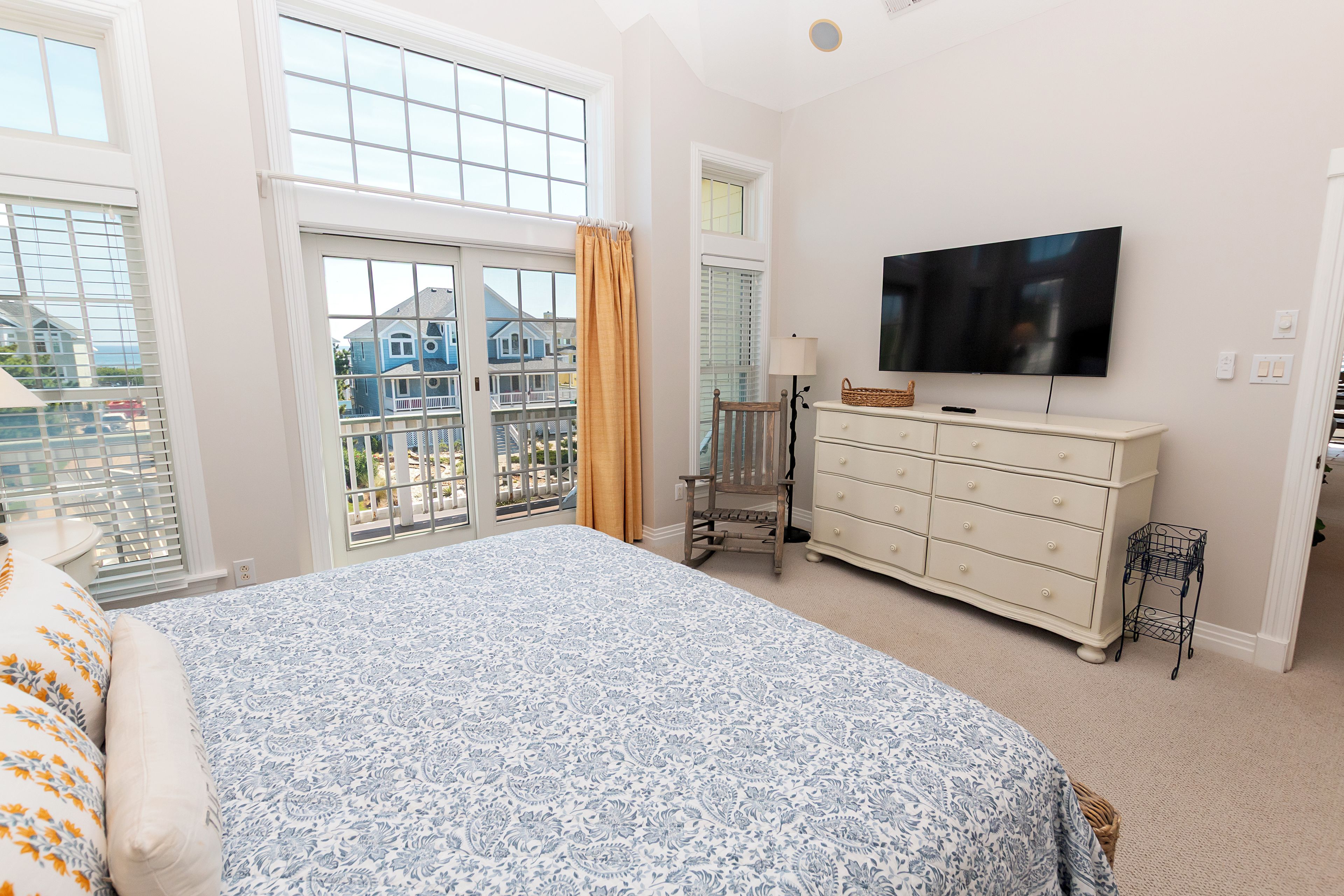 Ein Schlafzimmer mit einem großen Bett, einem Schminktisch, einem Fernseher und Blick ins Freie.