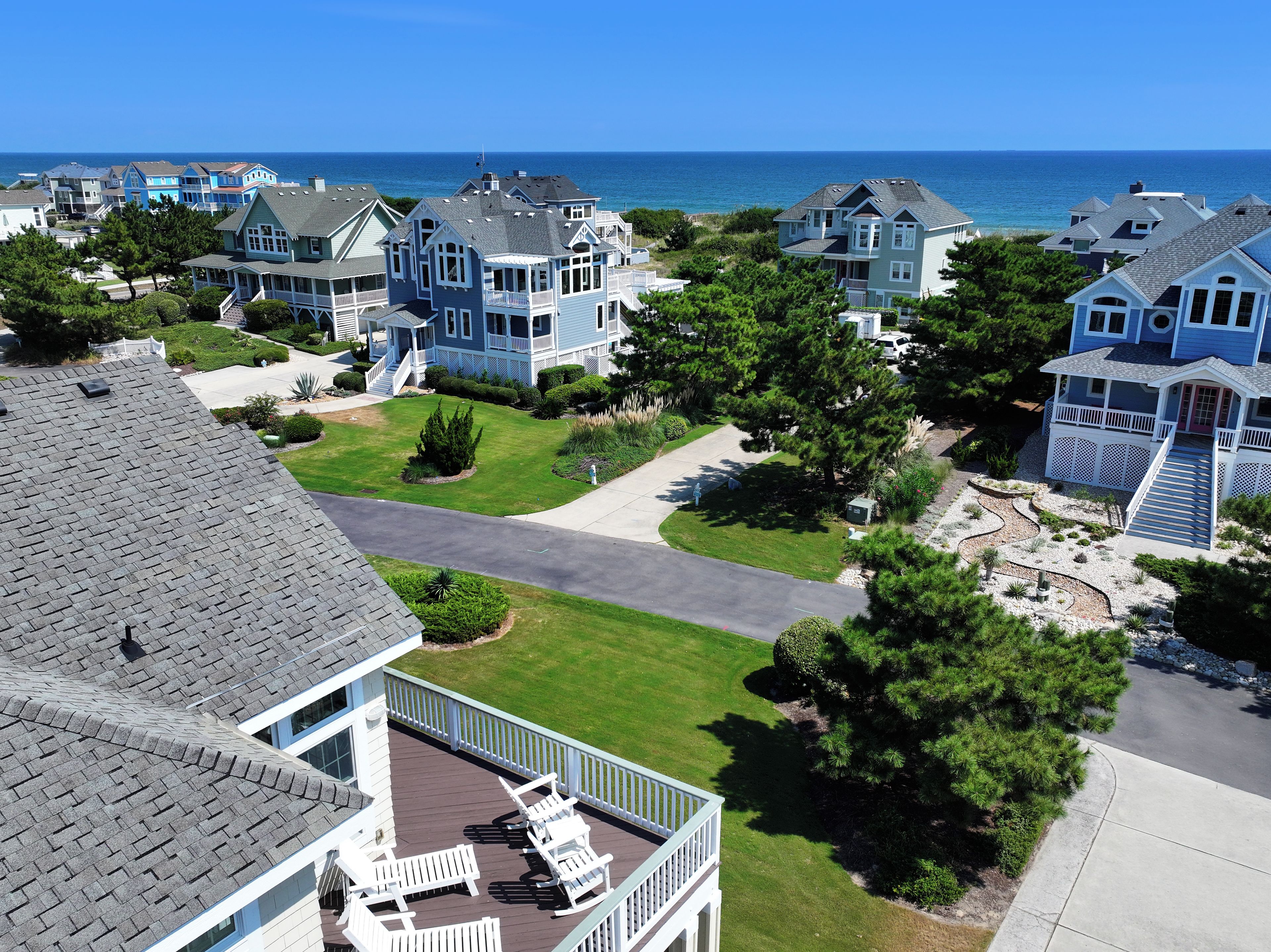 Un quartier résidentiel situé sur la côte, avec de nombreuses maisons à deux étages, un ciel dégagé et une vue sur l’océan.