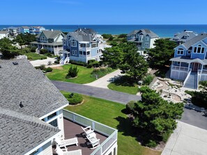 A coastal residential area with multiple two-story houses, a clear sky, and a view of the ocean.