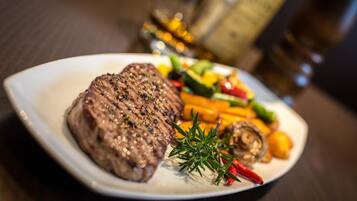 A plate with a steak, vegetables, and a sprig of rosemary.