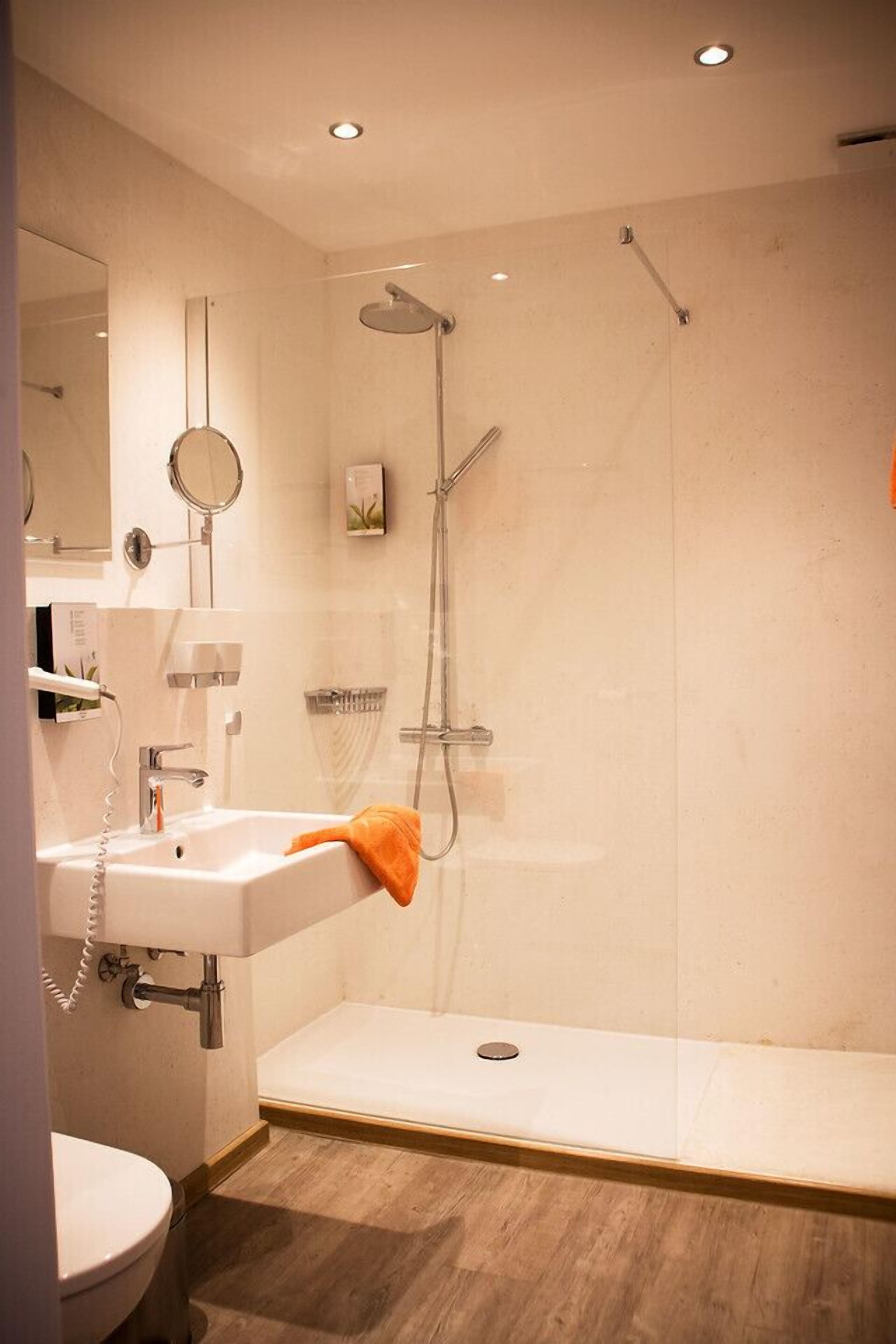 Un baño moderno con ducha, lavamanos e inodoro.