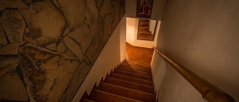 A staircase with stone walls and a wooden handrail.