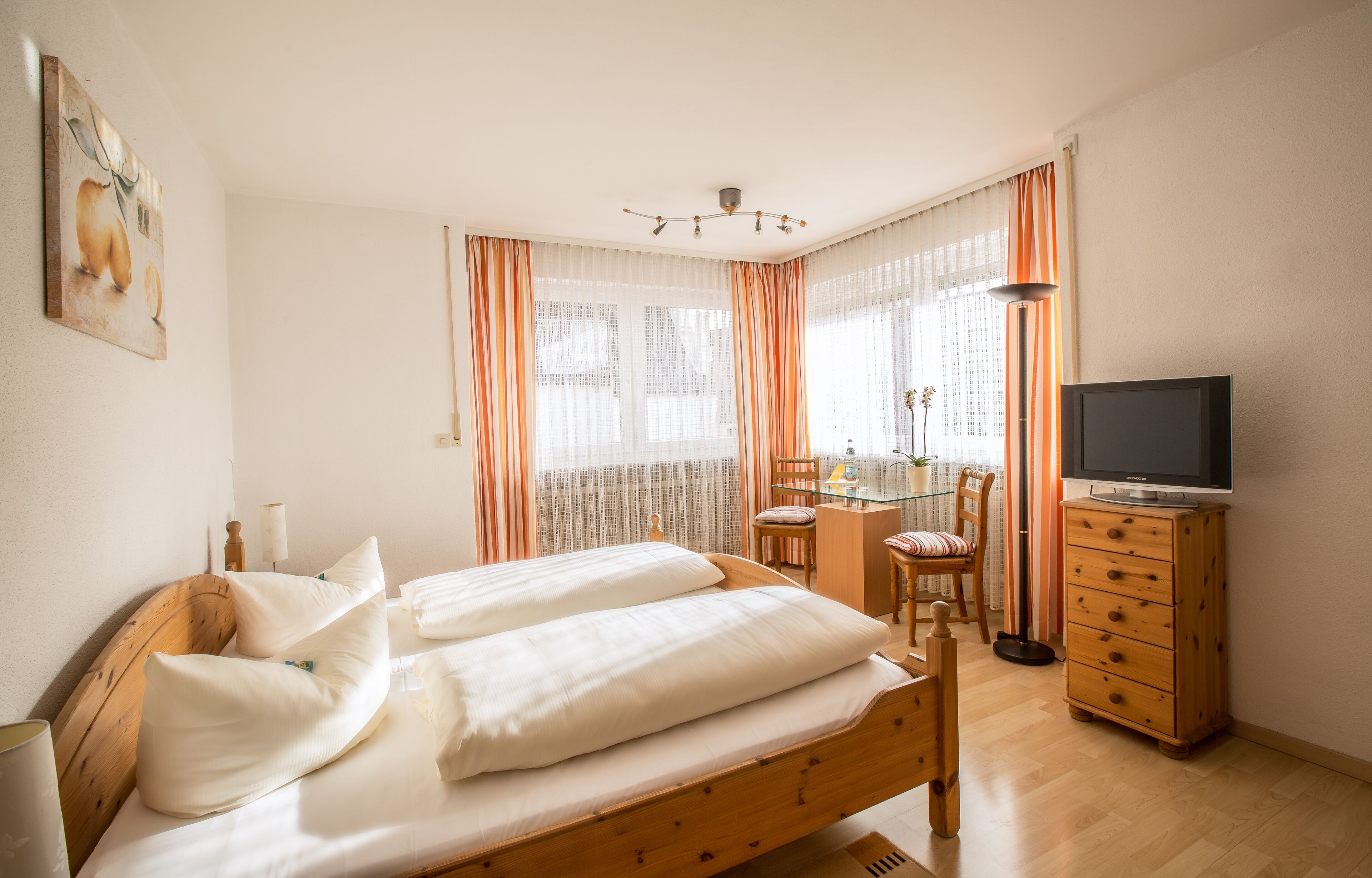 Ein Schlafzimmer mit einem hölzernen Bett, einem Schreibtisch, einem Stuhl, einem Fernseher und einer Kommode.