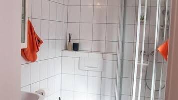 Un baño pequeño con inodoro, lavamanos y ducha.