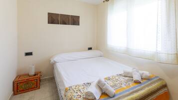 Una habitación de hotel con una cama, una mesita con una caja decorativa y una ventana con cortinas.