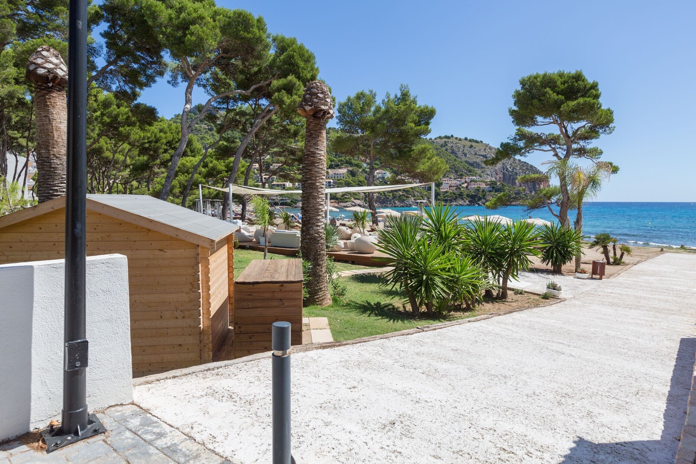 Una propiedad frente al mar con una cabaña de madera, un patio arenoso y vista al océano.
