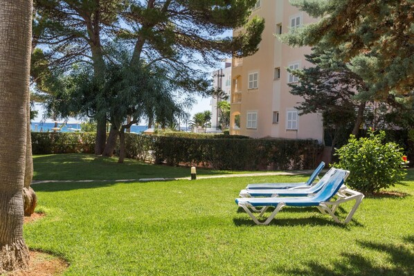 Un espace verdoyant avec deux fauteuils bleus et, au fond, un bâtiment doté de balcons.