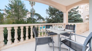 A balcony with a table and chairs, surrounded by greenery and buildings. - ORO DEL MAR IV Apartamento O2 - Apartment near the beach and with shared pool Free WiFi (Capdepera)