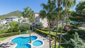 A resort with a large swimming pool, palm trees, and a view of the sea. - ORO DEL MAR IV Apartamento O2 - Apartment near the beach and with shared pool Free WiFi (Capdepera)