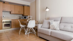 Una cocina moderna con armarios de madera, una mesa de comedor con sillas y un sofá beige con cojines decorativos.