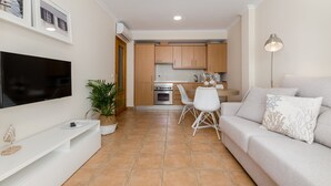 Una sala de estar moderna con una televisión de pantalla plana, un sofá y un comedor con sillas y una mesa.