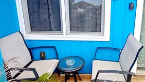 A room with two chairs and a small table, a window, and a sign that reads "MAHALO FOR REMOVING SHOES". - Spacious Waialua studio (Waialua)