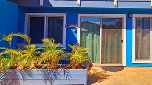 A blue building with white-framed windows and a sign for shoe removal. - Spacious Waialua studio (Waialua)