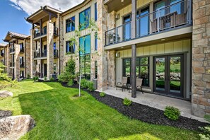 A multi-story residential building with stone facades, balconies, and a well-maintained lawn. - Luxe Canyons Condo w/ Golf Course Views! (Park City)