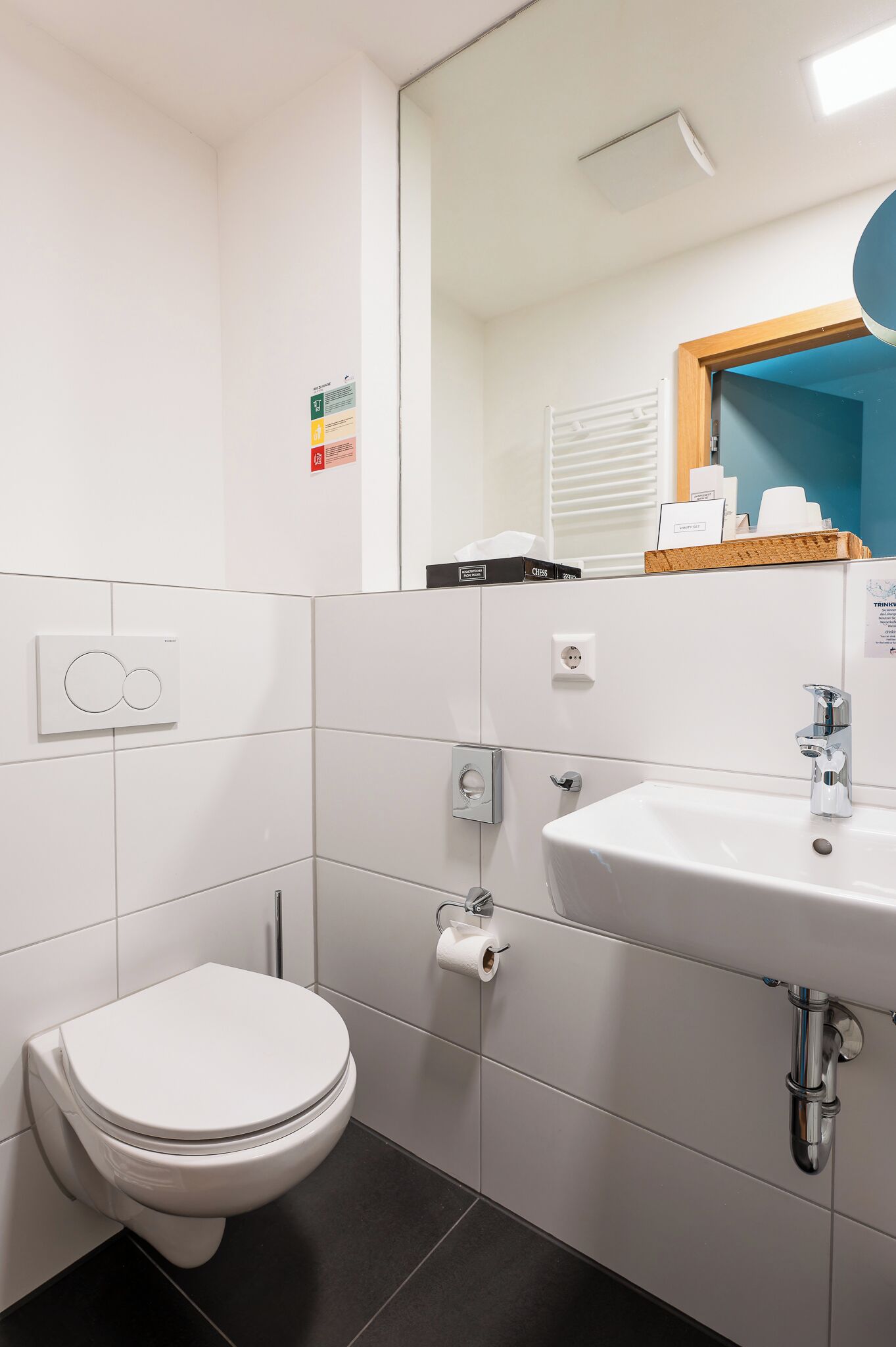 A modern bathroom with a toilet, sink, and mirror.