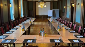 A conference room with long tables, red chairs, and a chandelier. - Schloss Horneck (Gundelsheim)