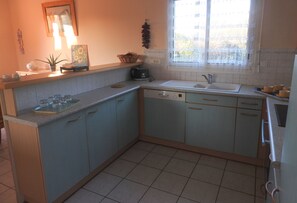 A kitchen with light blue cabinets, a sink, and a window with lace curtains.