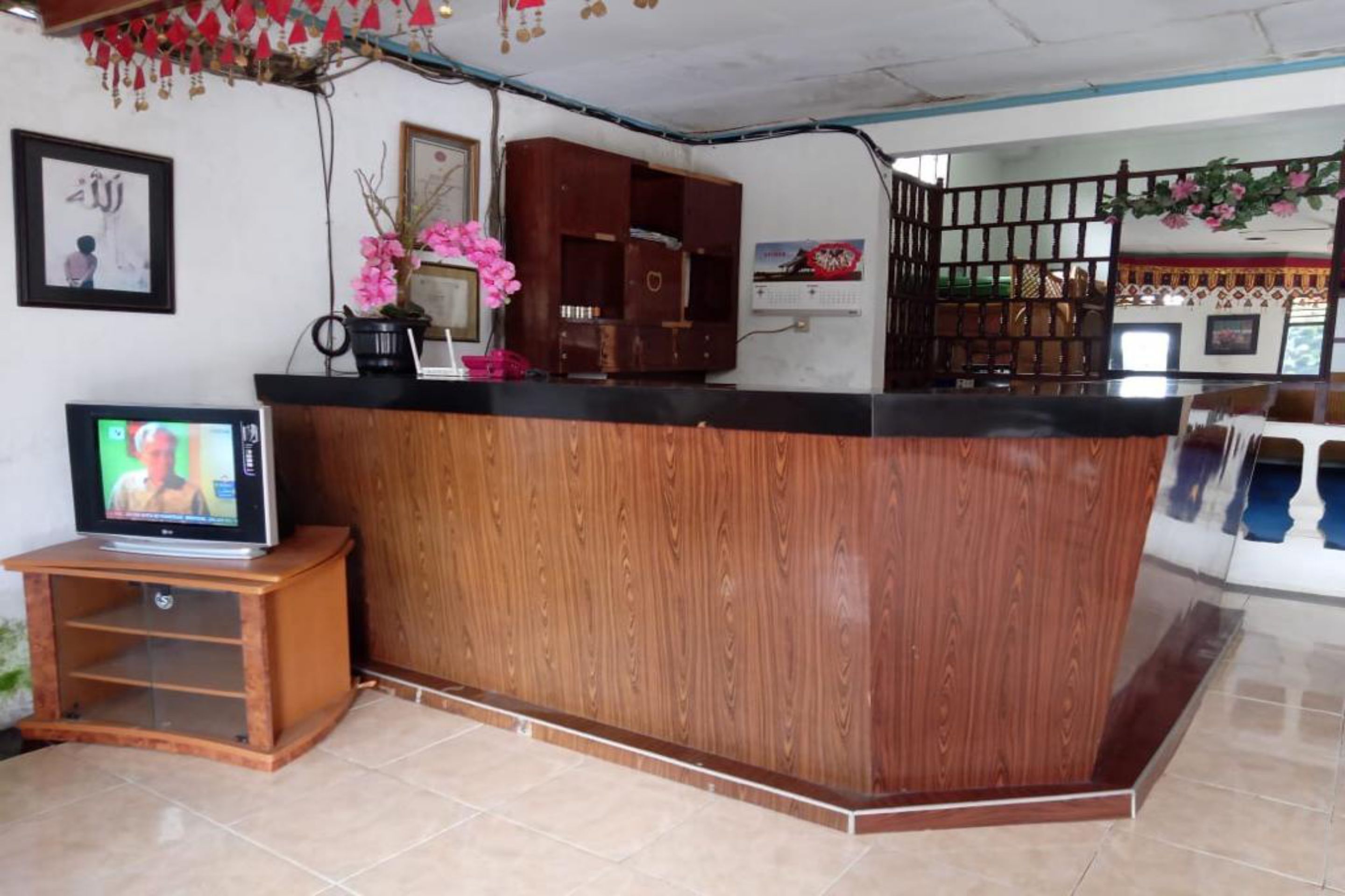 A reception area with a wooden counter, a television on a stand, and a decorative plant.