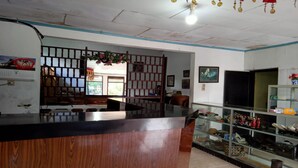 A reception area with a wooden counter, a glass display case, and a traditional partition. - OYO 2322 Dien Karona Hotel (Berastagi)