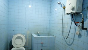 A small, tiled bathroom with a toilet, a shower area, and a water heater. - OYO 2322 Dien Karona Hotel (Berastagi)