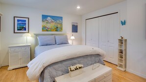 Quarto com cama, mesas de cabeceira, penteadeira e parede decorada com quadros.
