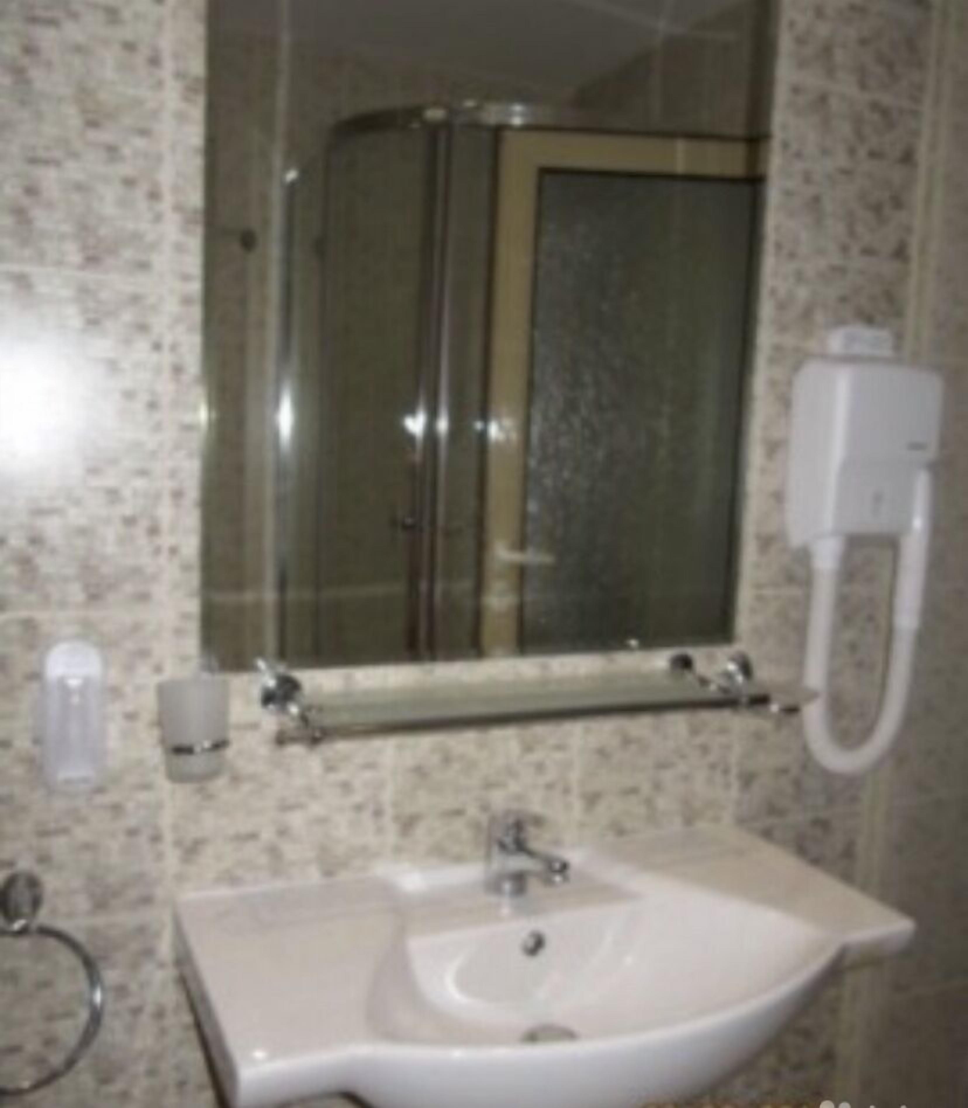 A bathroom with a sink, mirror, and shower.