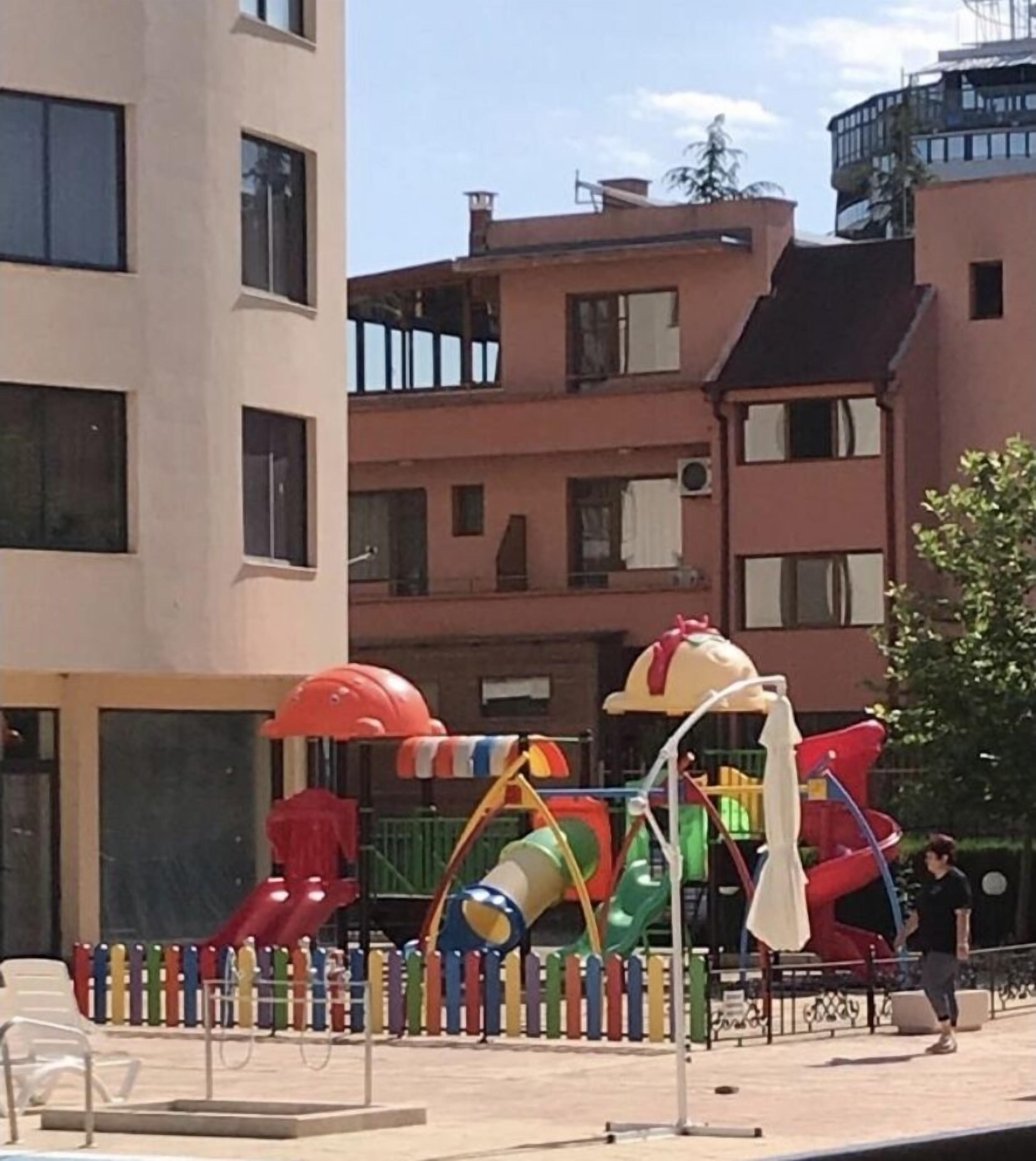 Un parque infantil con diversas estructuras de juego, rodeado de edificios de apartamentos.