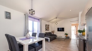 Una sala de estar moderna con una mesa de comedor, sillas, un sofá y un televisor.