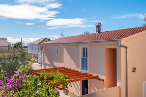 A residential building with a red-tiled roof, a staircase leading to the entrance, and a small garden with pink flowers. - Villa Jadranka Privlaka (Privlaka)