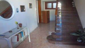 A staircase with a wooden handrail and a tiled floor.