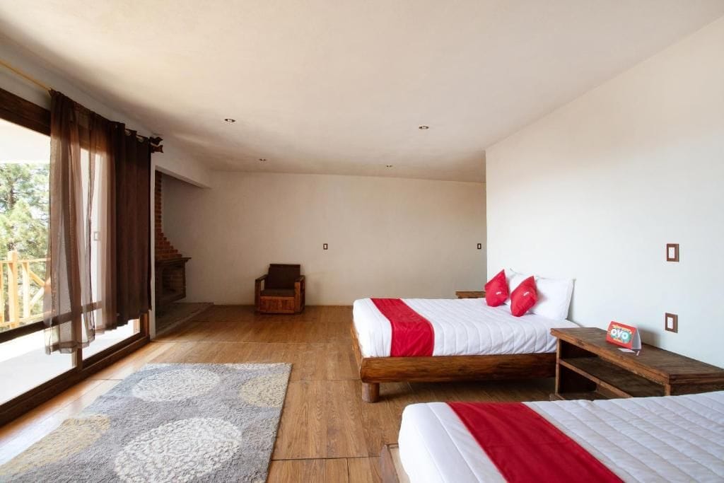 A bedroom with two beds, a wooden floor, a fireplace, and a view of the outdoors.
