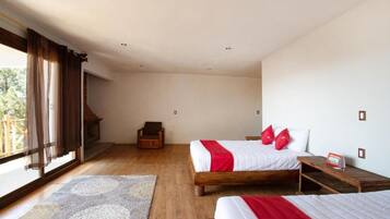 A bedroom with two beds, a wooden floor, a fireplace, and a view of the outdoors.