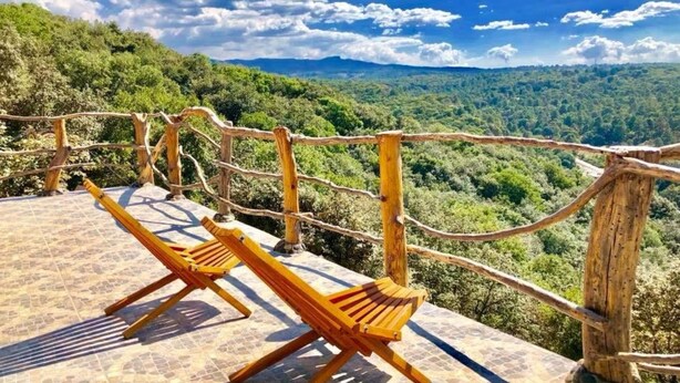 Un banco de madera con vistas a un paisaje montañoso y un cielo despejado.