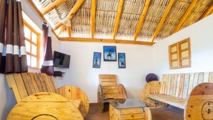 Una habitación con techo de paja, muebles de madera, un televisor y cuadros colgados en la pared.