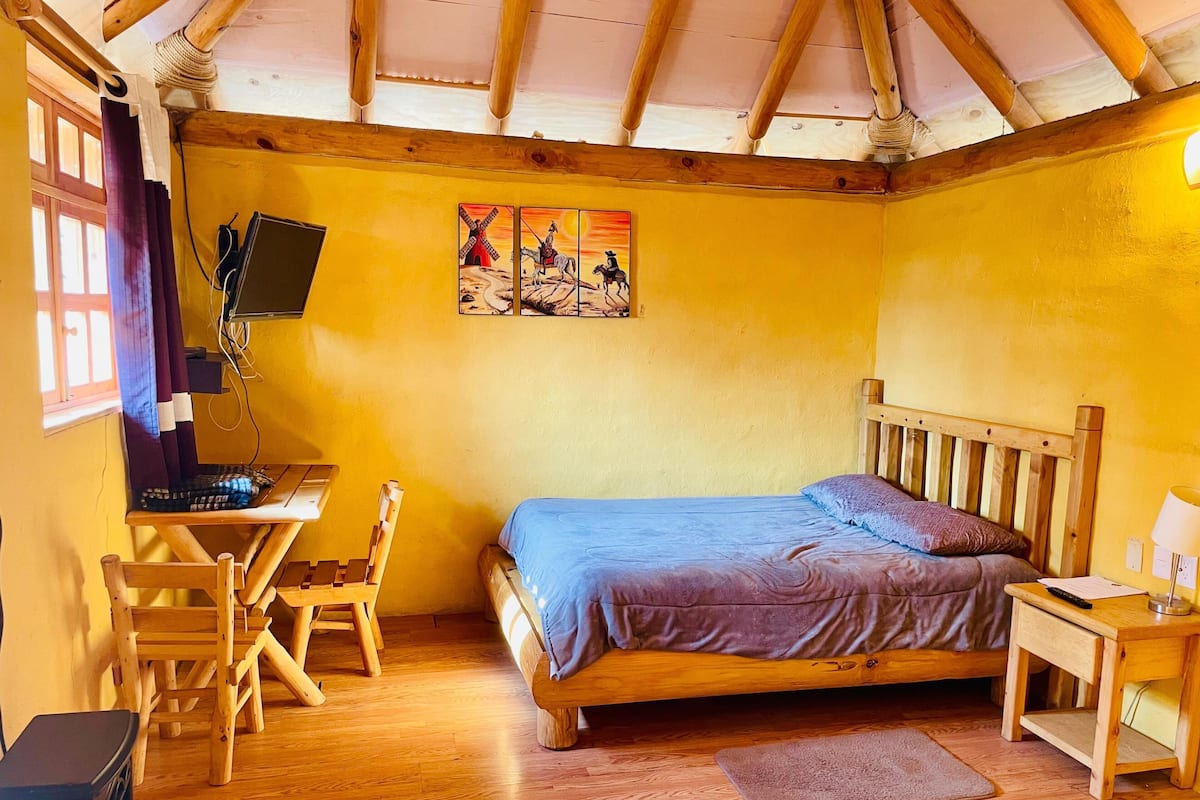 A cozy room with a wooden bed, a desk with a computer, and a chair.
