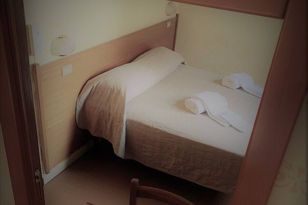 A single bed with a wooden headboard, a small bedside table, and a chair.