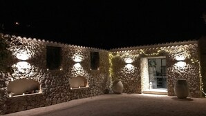 Une cour bordée de murs en pierre, au charme rustique, éclairée d’une lumière douce.