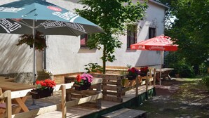 Bancos de madera al aire libre con jardineras incorporadas, una mesa y dos sombrillas.
