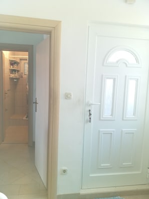 A room with a white door, a bathroom with a shower, and a hallway leading to another room. - Apartments Ivan (Tribunj)