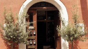 A building entrance with a detailed relief sculpture above the door, a signboard, and two potted plants on either side. - Hotel am Fischmarkt (Konstanz)
