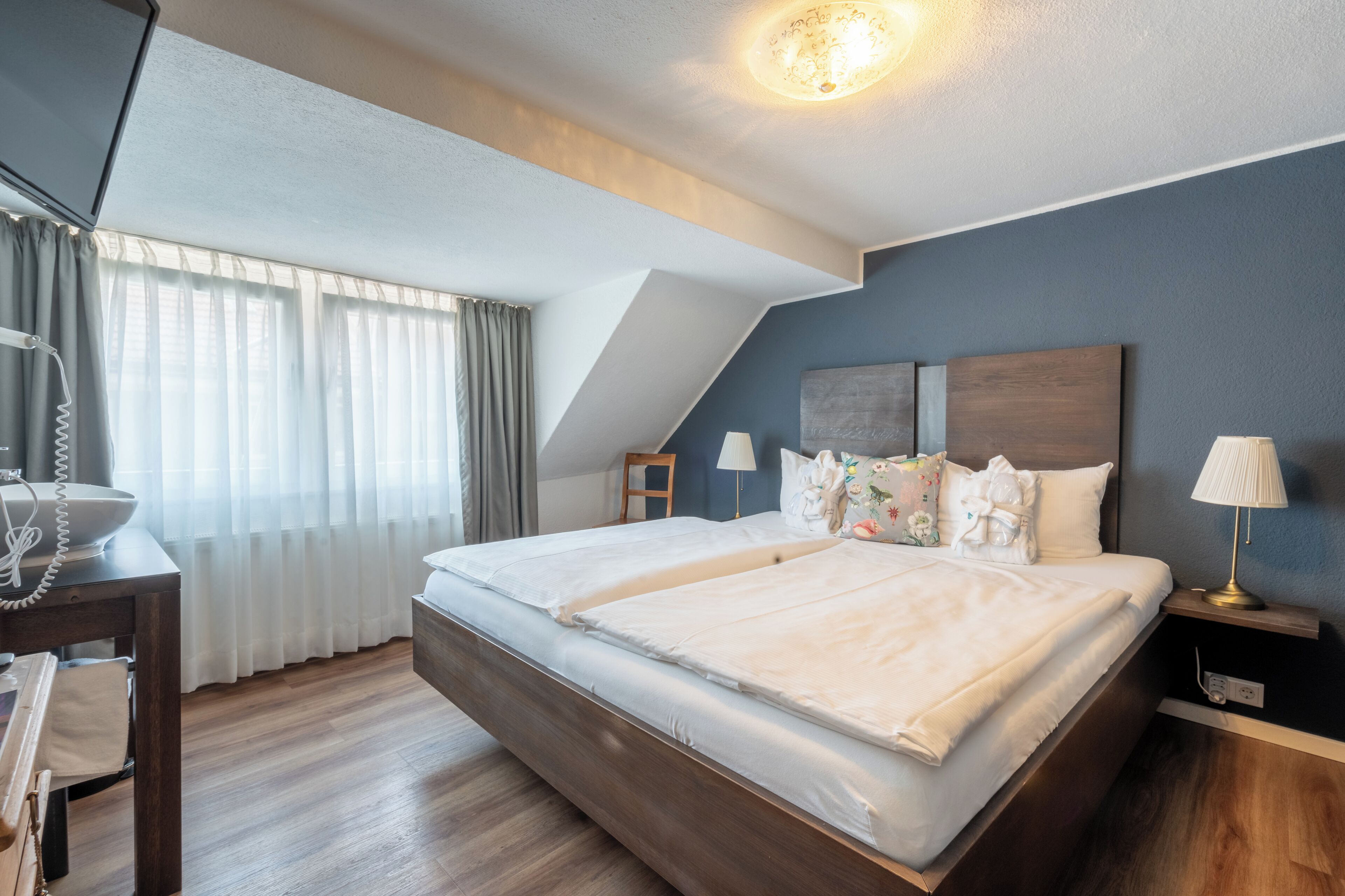 Een moderne hotelkamer met een groot bed, een bureau met telefoon en een lamp.