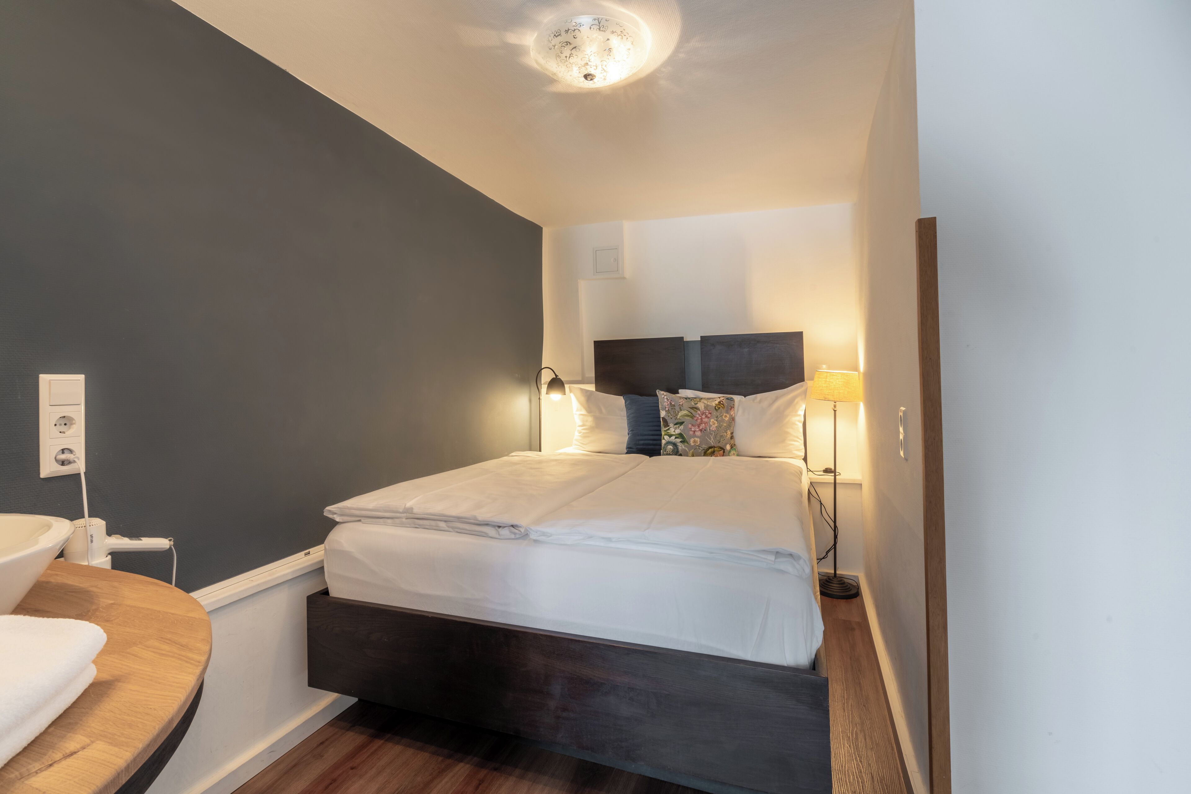 Ein modernes Schlafzimmer mit dunklem Kopfteil, einer Nachttischlampe und einem Nachttisch.