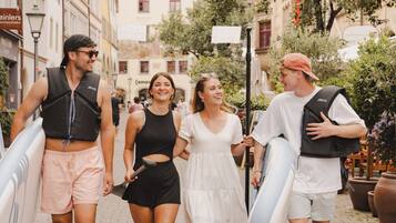 Un gruppo di persone cammina su una strada acciottolata, alcune con tavole da surf.