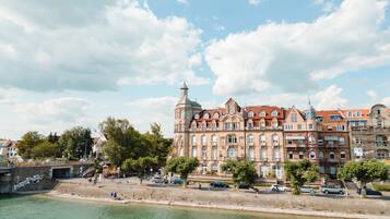 A waterfront building with multiple stories, large windows, and a prominent tower.