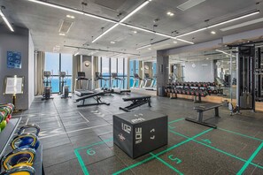 A modern gym with treadmills, weight benches, and kettlebells.