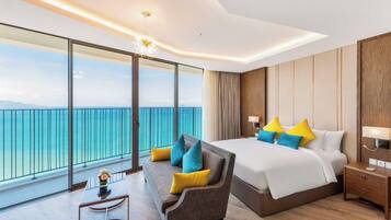 Une chambre d’hôtel avec un grand lit, un canapé, une petite table et une vue sur la mer.