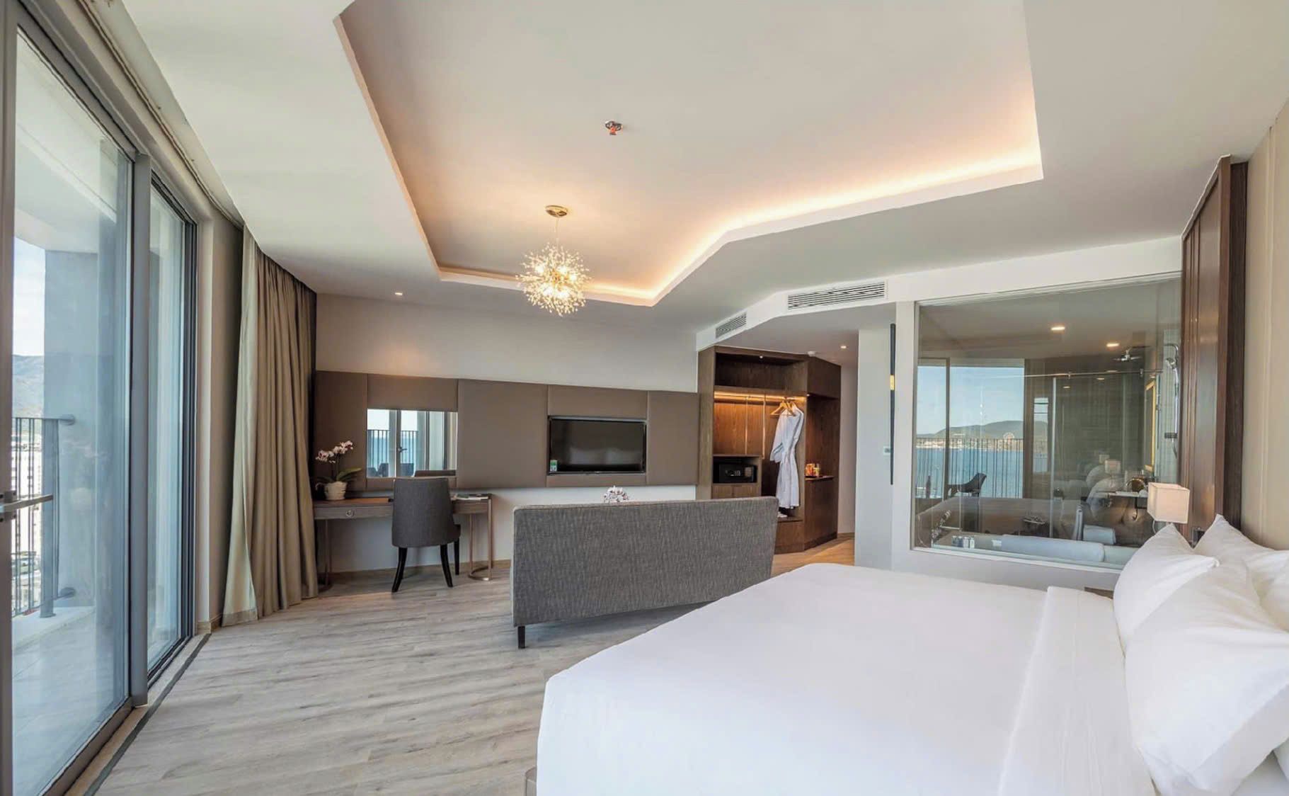 Una habitación de hotel moderna con una cama grande, un escritorio con silla, una televisión y un vestidor.